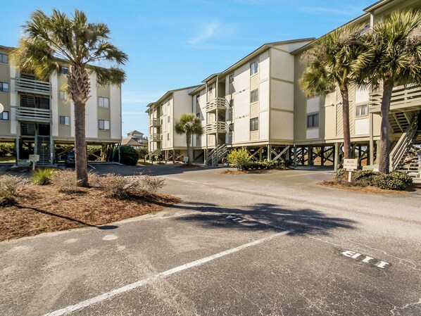 Ein mehrstöckiges Hotel mit Parkplatz und Palmen.