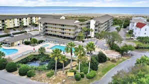 A hotel with multiple floors, a swimming pool, and a view of the beach.
