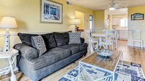 A living room with a gray sofa, patterned pillows, a wooden coffee table, and a framed picture on the wall.