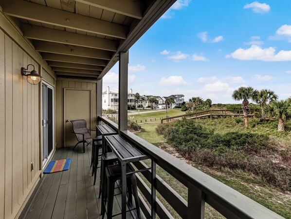 A covered outdoor area with a wooden deck, a bench, and a table. - 2BR/2BA Oceanfront + Private Beach Access + Dolphins + Pool + Balcony (Tybee Island)