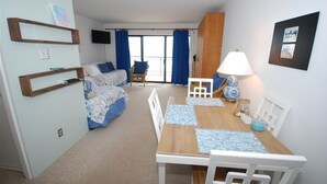 Un espacio habitable compacto con un sofá, una mesa de comedor y un televisor montado en la pared.