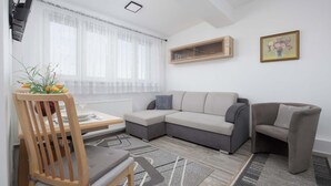 A modern living room with a sectional sofa, a wooden dining table, and a chair.