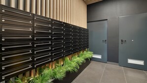 A row of black lockers with numbers, a wooden slatted wall behind, and a door to the right.