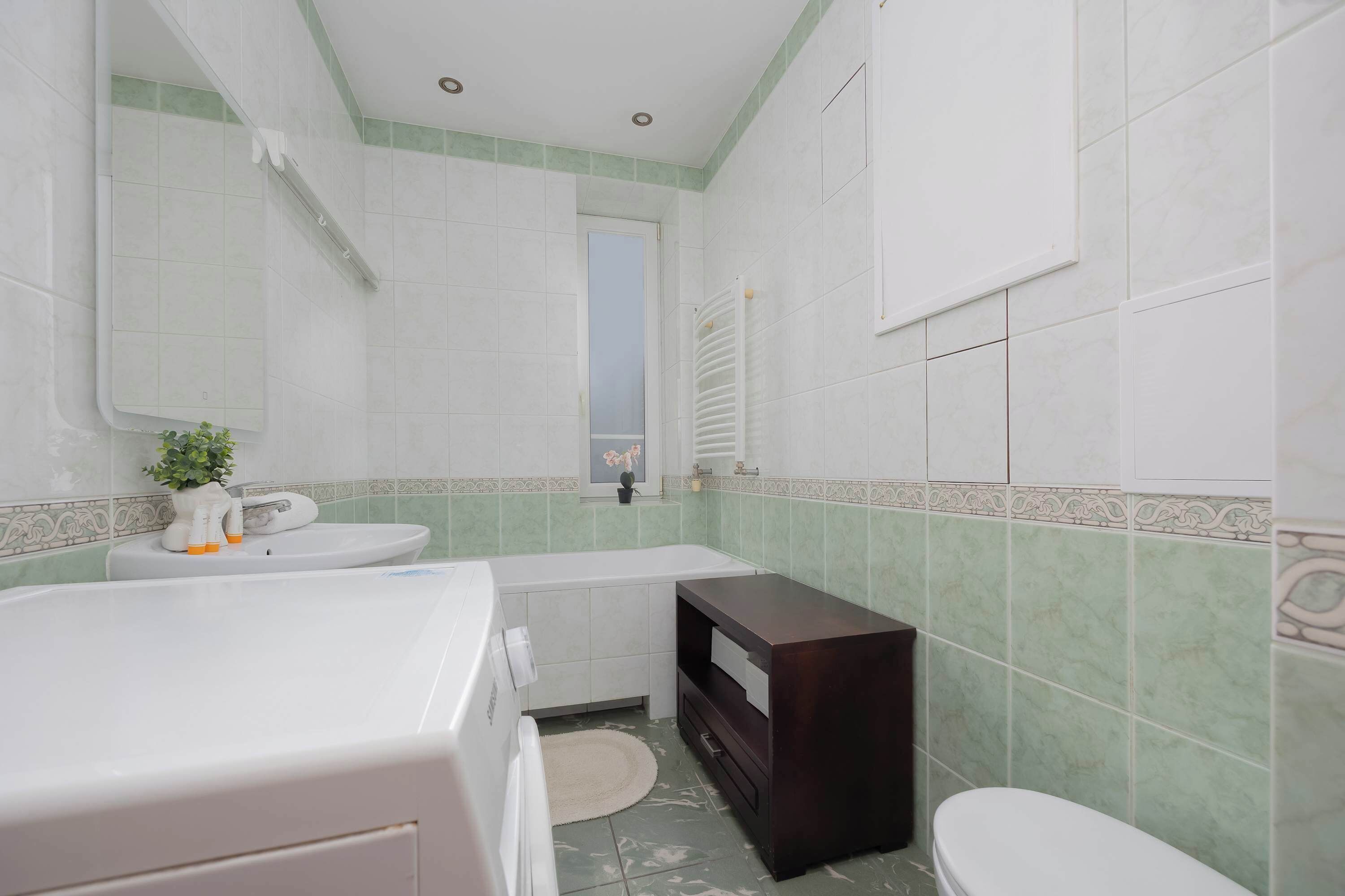 A bathroom with a white bathtub, a white sink, and a dark wooden vanity.