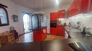 A kitchen with red cabinets, a black countertop, and a stainless steel sink. - Apartment in the centre of Mijas Pueblo with a large terrace and sea views (Mijas)