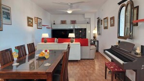 A living room with a dining table, sofa, and piano. - Apartment in the centre of Mijas Pueblo with a large terrace and sea views (Mijas)