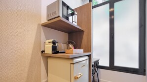 Uma cozinha compacta com micro-ondas, torradeira e cafeteira em uma bancada pequena.