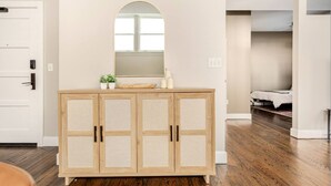 Un meuble en bois avec un miroir au-dessus, une petite plante et quelques bouteilles posées sur le dessus.