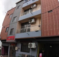 A multi-story building with balconies, air conditioning units, and a visible storefront with signage.