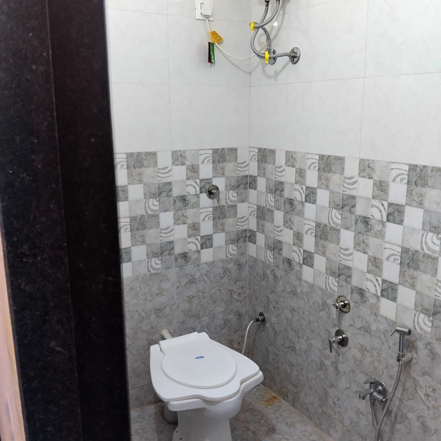 Un bagno con il water, una doccia e un muro rivestito di piastrelle a scacchi.
