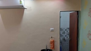 Ένα μπάνιο με νιπτήρα, μια κρεμάστρα για πετσέτες και μια περιοχή με ντους, η οποία είναι ορατή μέσα από μια γυάλινη πόρτα.