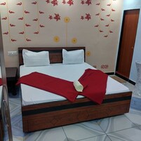 A neatly made bed with white bedding, a wooden headboard, and a red blanket.