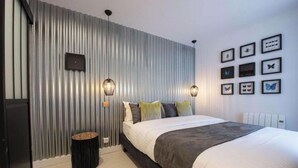 A modern bedroom with a large bed, a wall-mounted TV, and decorative butterfly wall art. - A PERFECT BLEND OF CHARACTER, COMFORT &ARCHITECTURAL CHARM-RUE DU TEMPLE- MARAIS (Paris)