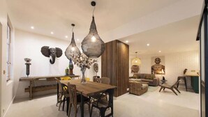 A modern living room with a dining area, featuring a wooden table, chairs, and a sofa. There are decorative items on the walls and a large sculpture in the background. - A PERFECT BLEND OF CHARACTER, COMFORT &ARCHITECTURAL CHARM-RUE DU TEMPLE- MARAIS (Paris)