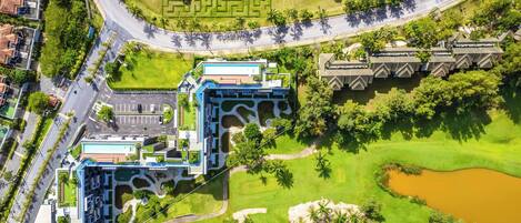 Vista aérea de un hotel moderno con un patio central, piscina y campo de golf.