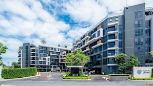 Un immeuble moderne à plusieurs étages, doté d’un parking, d’un panneau indiquant un « Skypark » et offrant une vue sur un ciel dégagé.