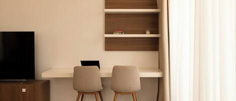 A modern living room with a flat-screen TV, two chairs, a wooden cabinet, and a built-in shelf unit.