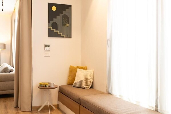 Una habitación moderna con sofá cama, una mesita auxiliar y una obra de arte colgada en la pared.