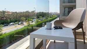 Ein Balkon mit einem weißen Tisch, einem Korbstuhl und einer Sonnenbrille.