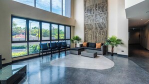 Eine geräumige Lobby mit großen Fenstern, einer hohen Decke und einer dekorativen Wand.