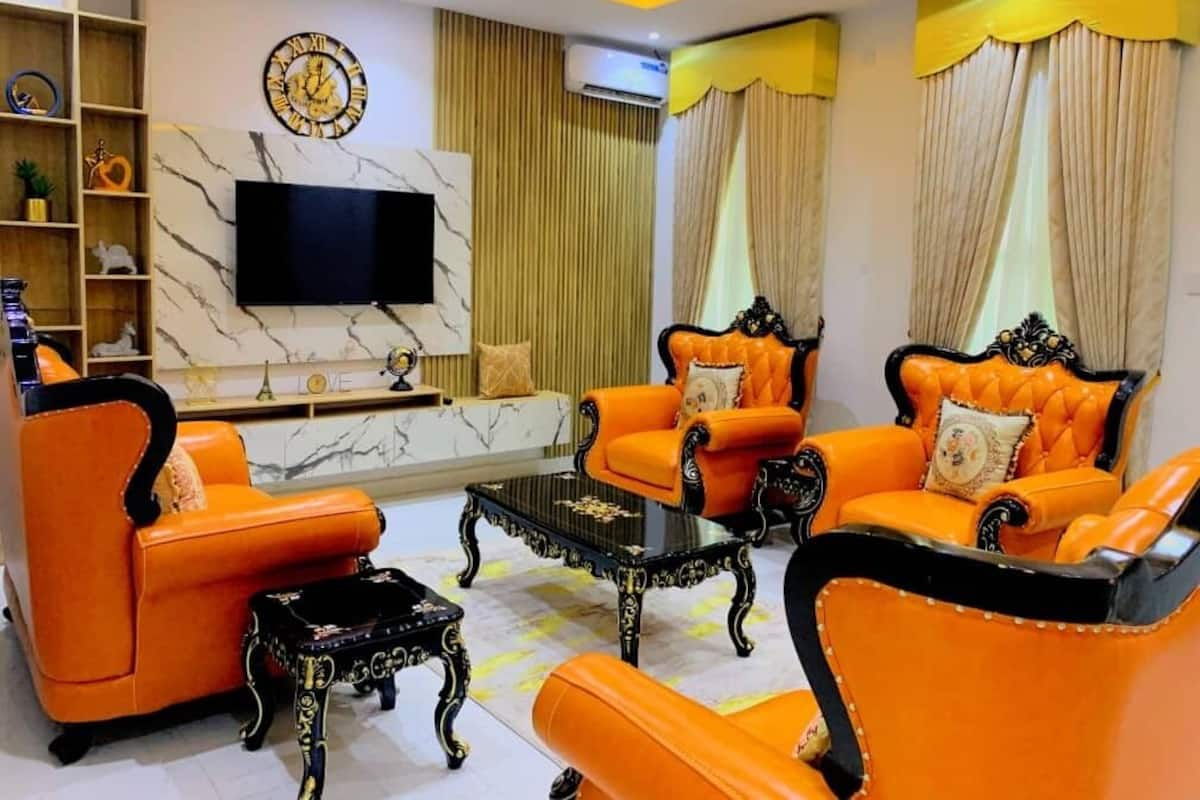 A living room with orange leather sofas, a black coffee table, and a marble wall with a clock.