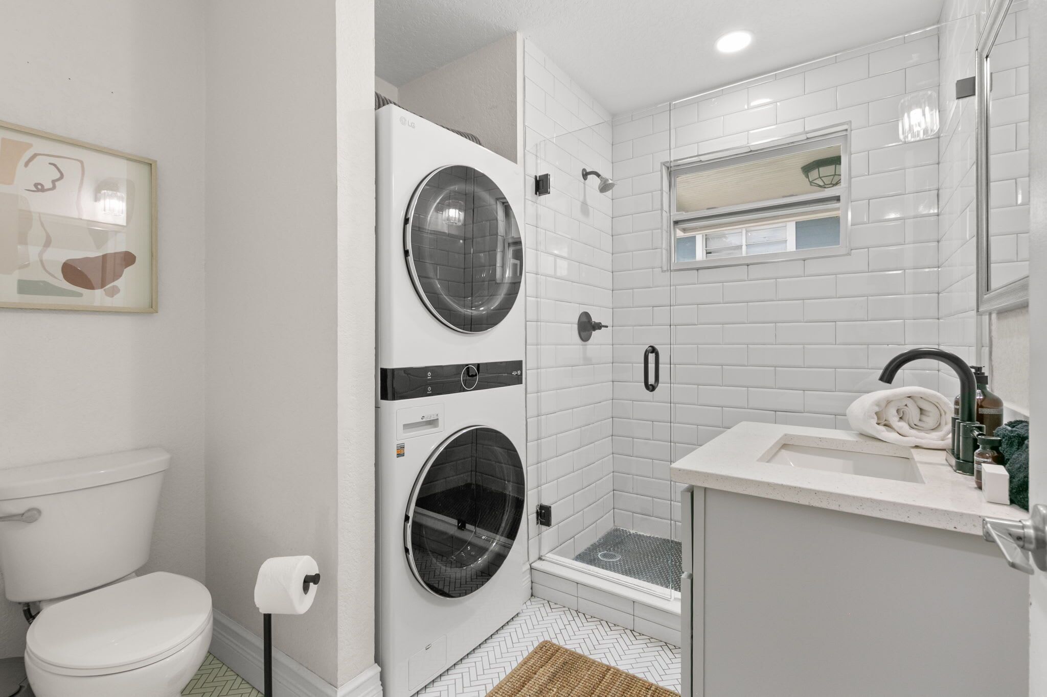 Une petite salle de bain comprenant des toilettes, un lave-linge, une douche et un lavabo.