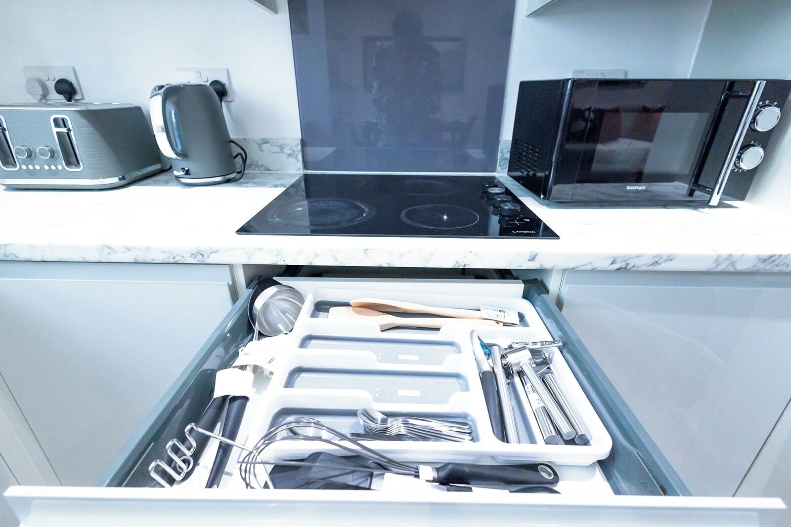 Une cuisine équipée d’un four à micro-ondes, d’un grille-pain et d’une cuisinière intégrés. Un tiroir situé en dessous contient divers ustensiles et ustensiles de cuisine.