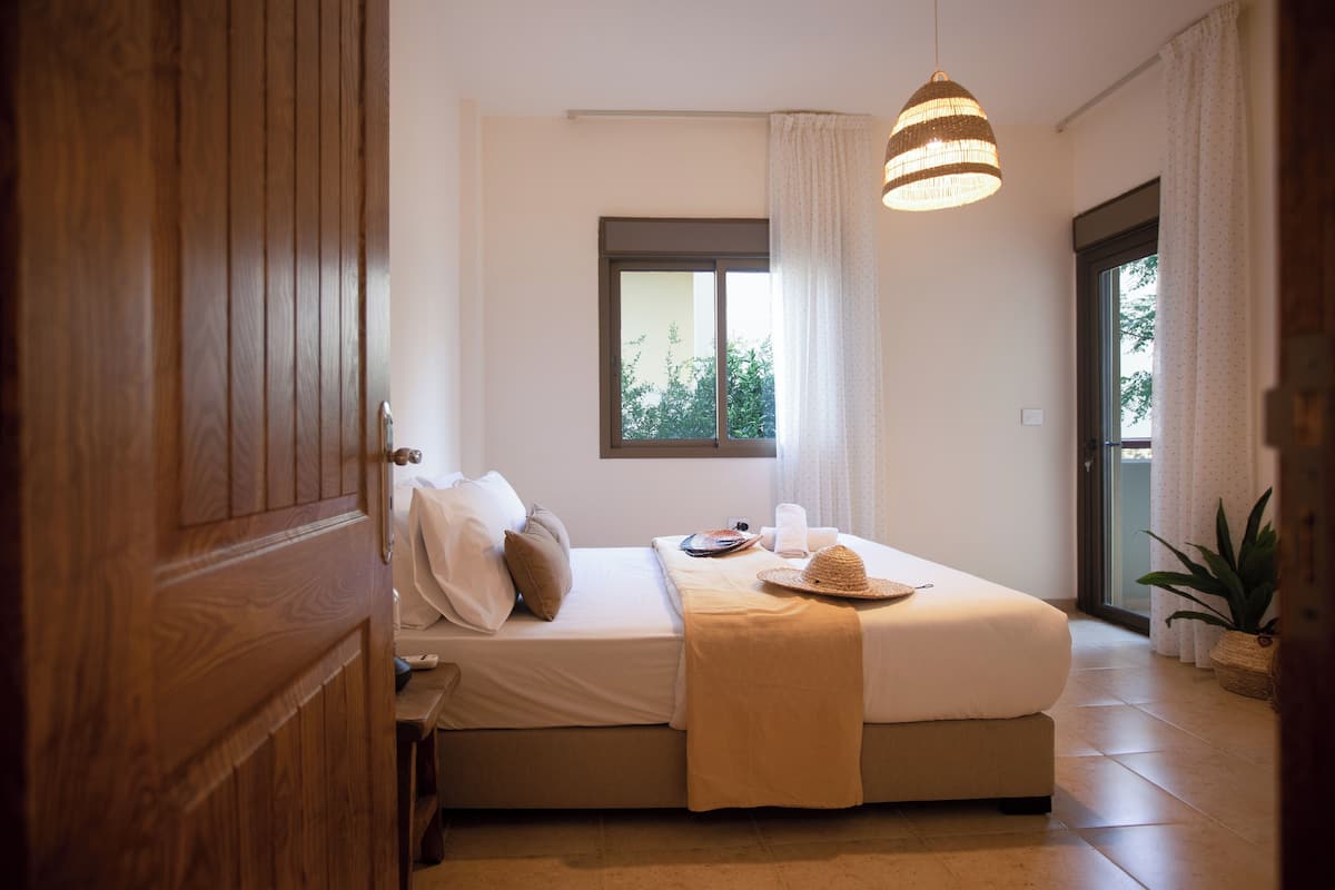 A bedroom with a bed, bedside table, window, and a hanging light fixture.