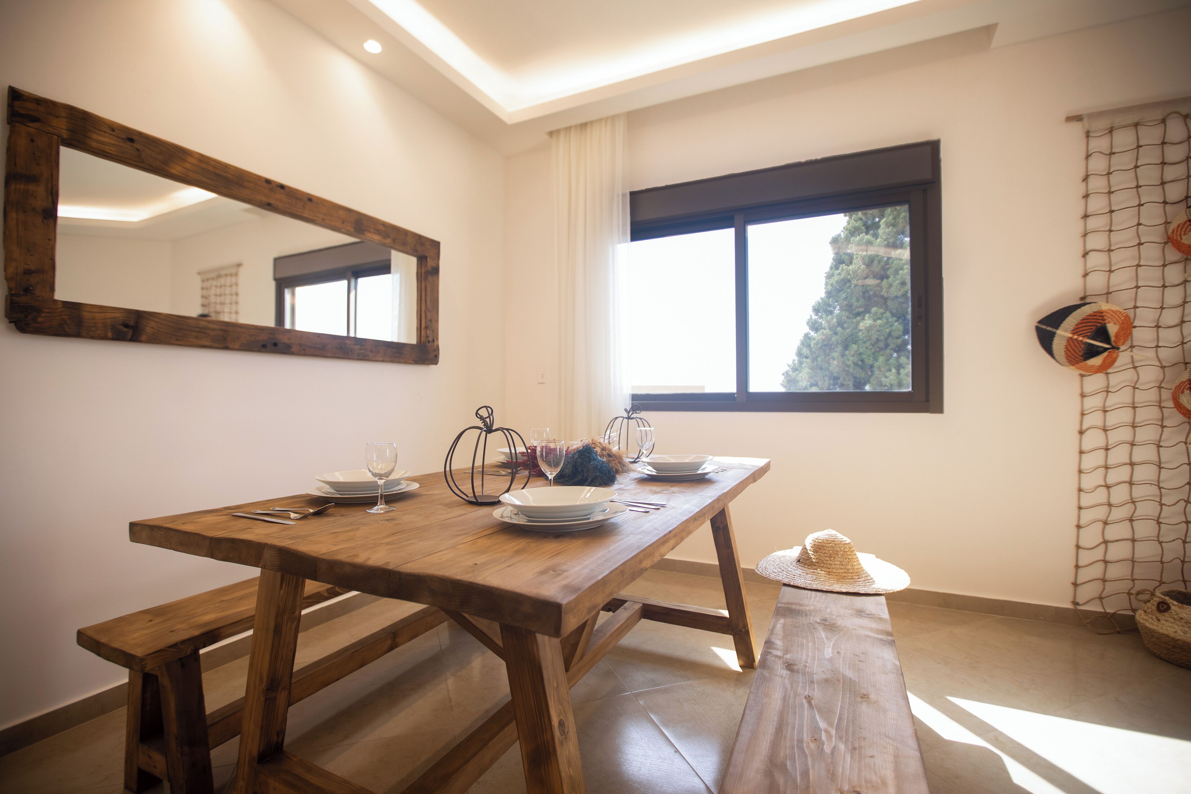A wooden dining table with plates, glasses, and cutlery.