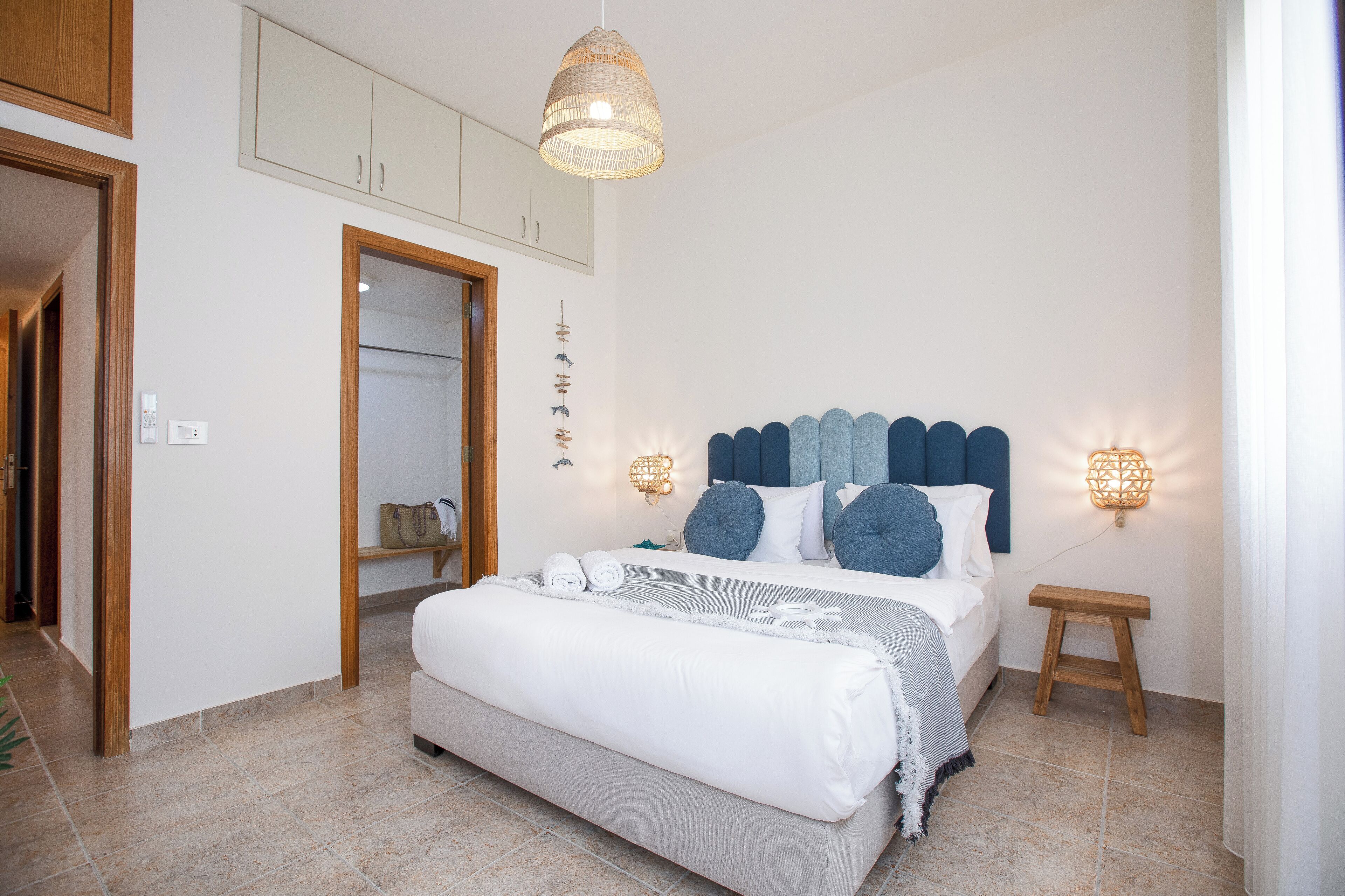 Een slaapkamer met een bed, nachtkastjes, een kledingkast en een hanglamp.