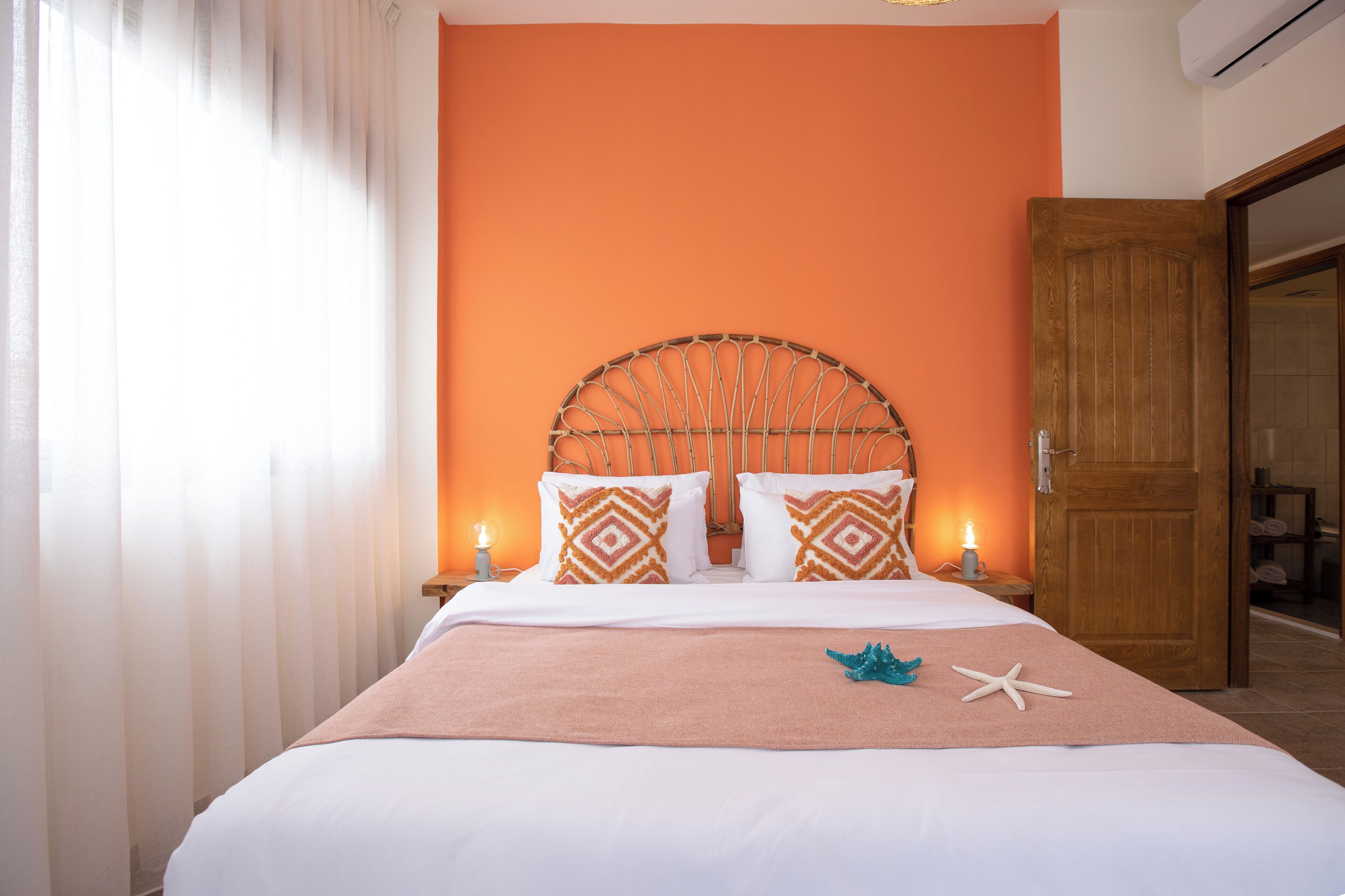 Un lit bien fait, avec une tête de lit en bois, une literie blanche et des coussins décoratifs.