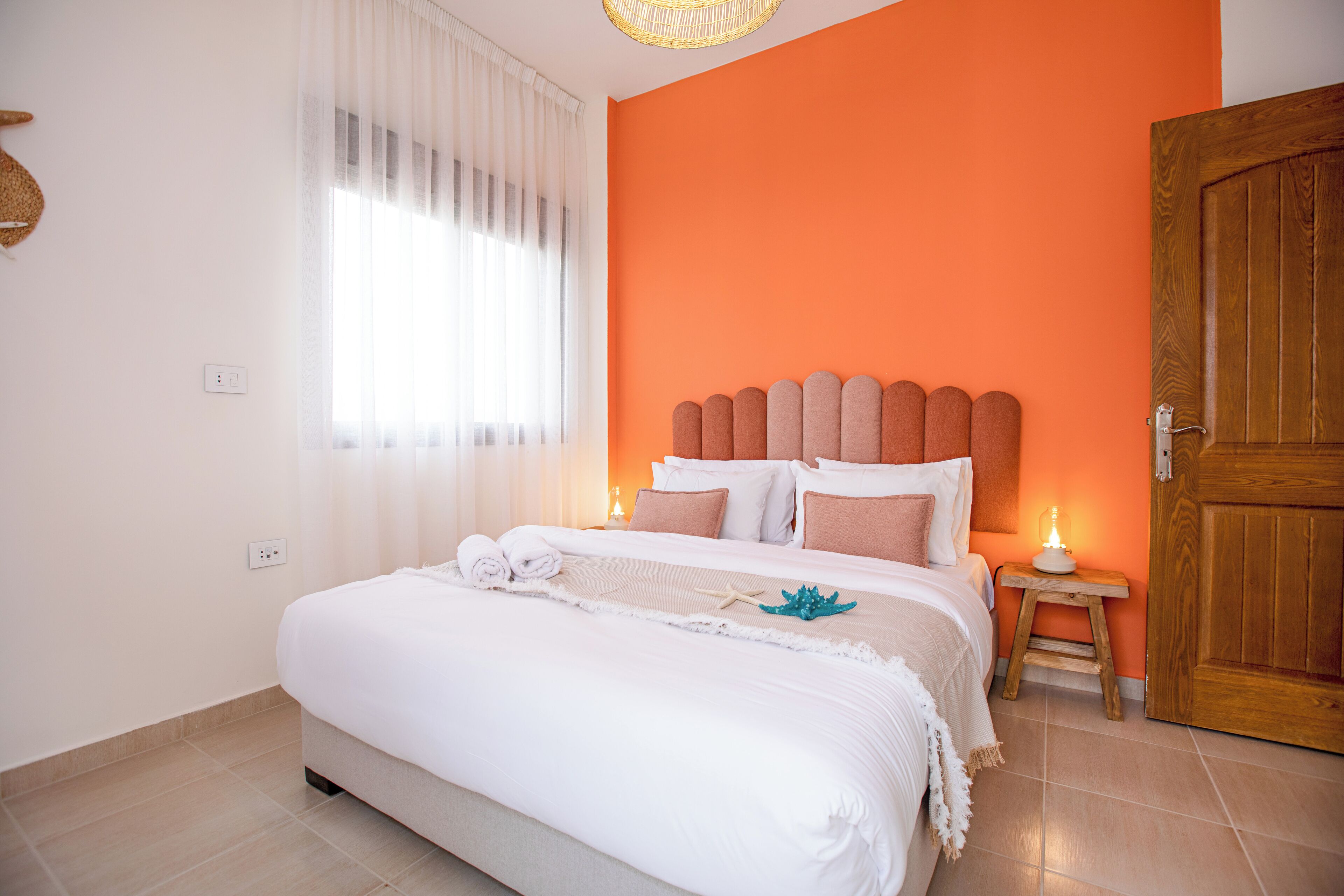 A neatly made bed with white linens and a decorative starfish.
