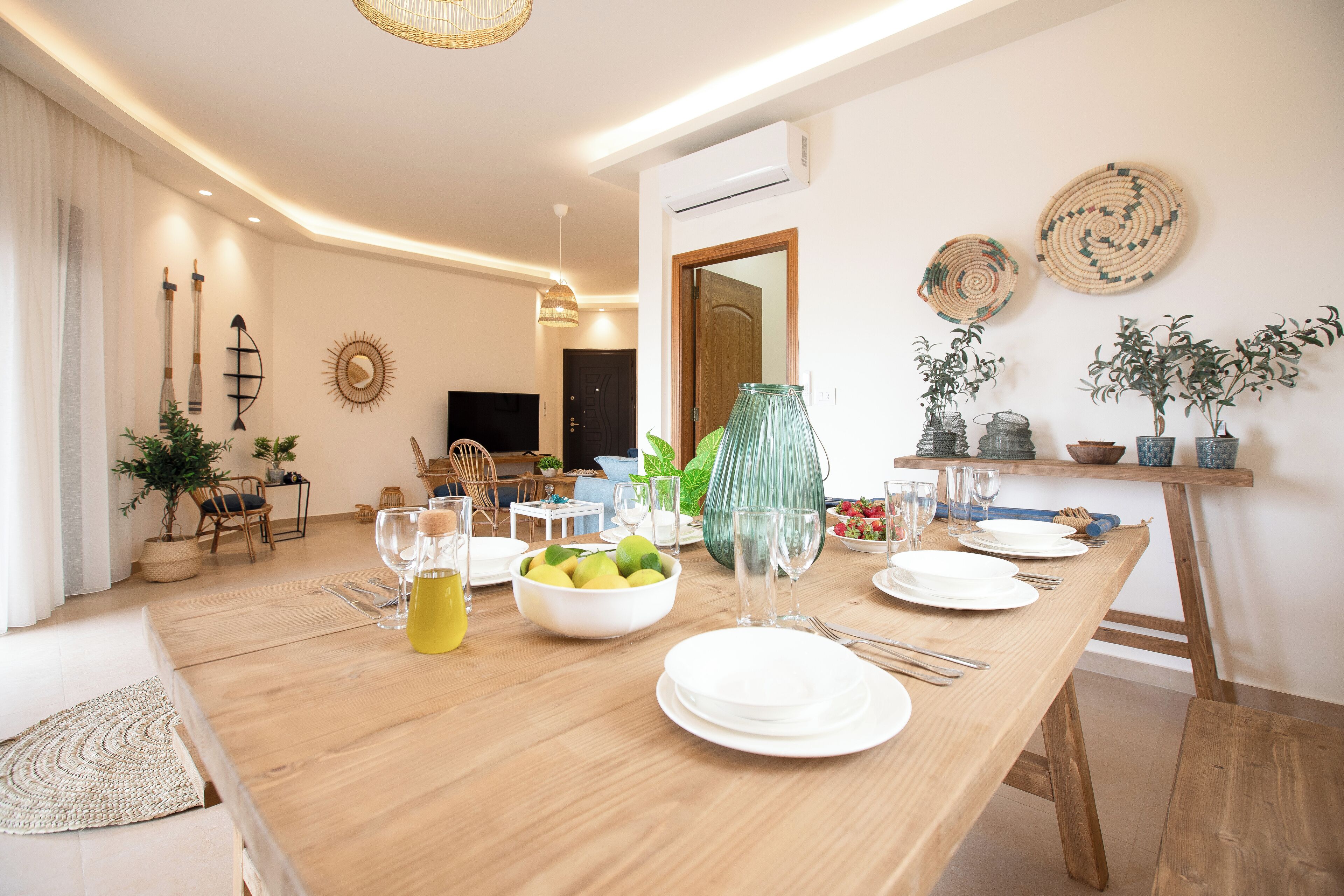 Een eetgedeelte met een houten tafel gedekt voor een maaltijd, omringd door stoelen, een buffet en decoratieve voorwerpen.