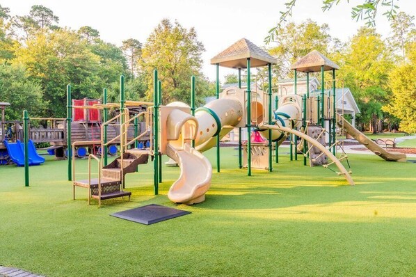 Ein Spielplatz mit Rutsche, Klettergerüsten und einem überdachten Spielbereich.