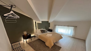 A modern bedroom with a bed, bedside tables, a hanging clothes rack, and a large window with curtains. - Lucciano Suite - Apartment with two bedrooms and bathroom (Quarrata)