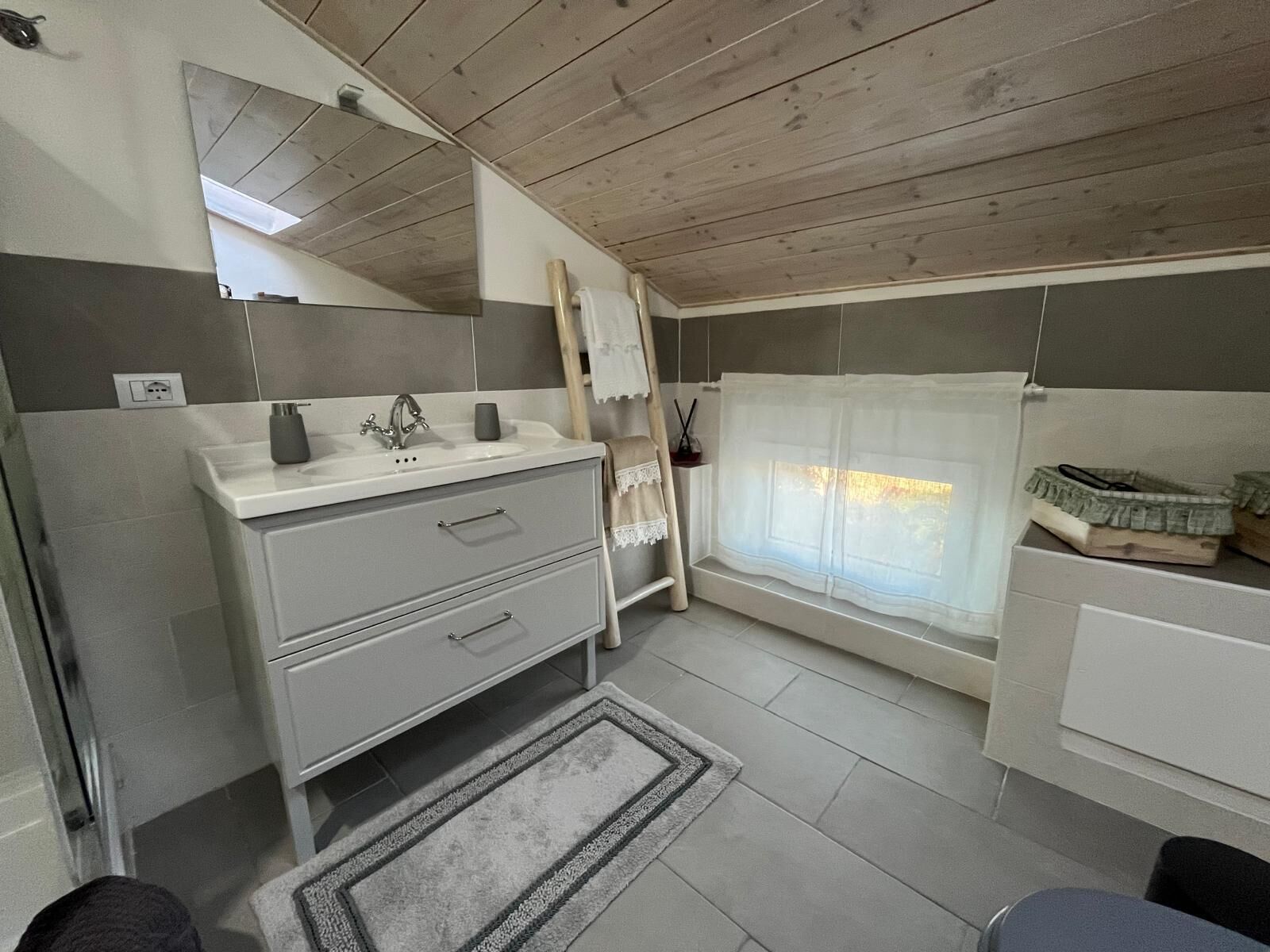 Un baño moderno con lavamanos, espejo y ventana.