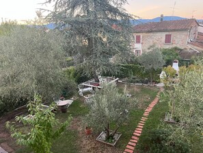 A garden with a white metal bench, a small tree, and a brick pathway. - Lucciano Suite - Apartment with two bedrooms and bathroom (Quarrata)