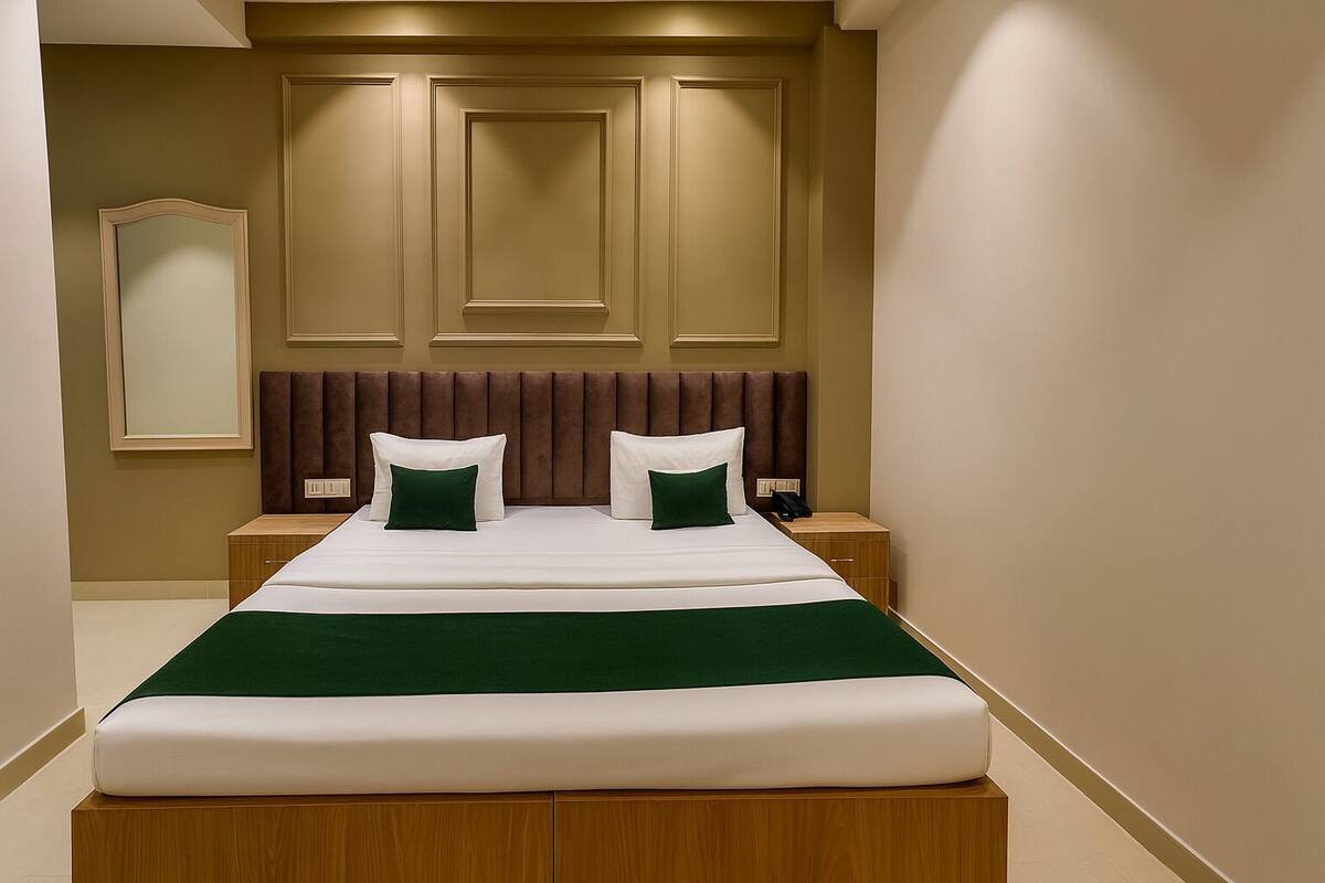 Een hotelkamer met een groot bed, een houten hoofdeinde, een nachtkastje en een spiegel aan de muur.