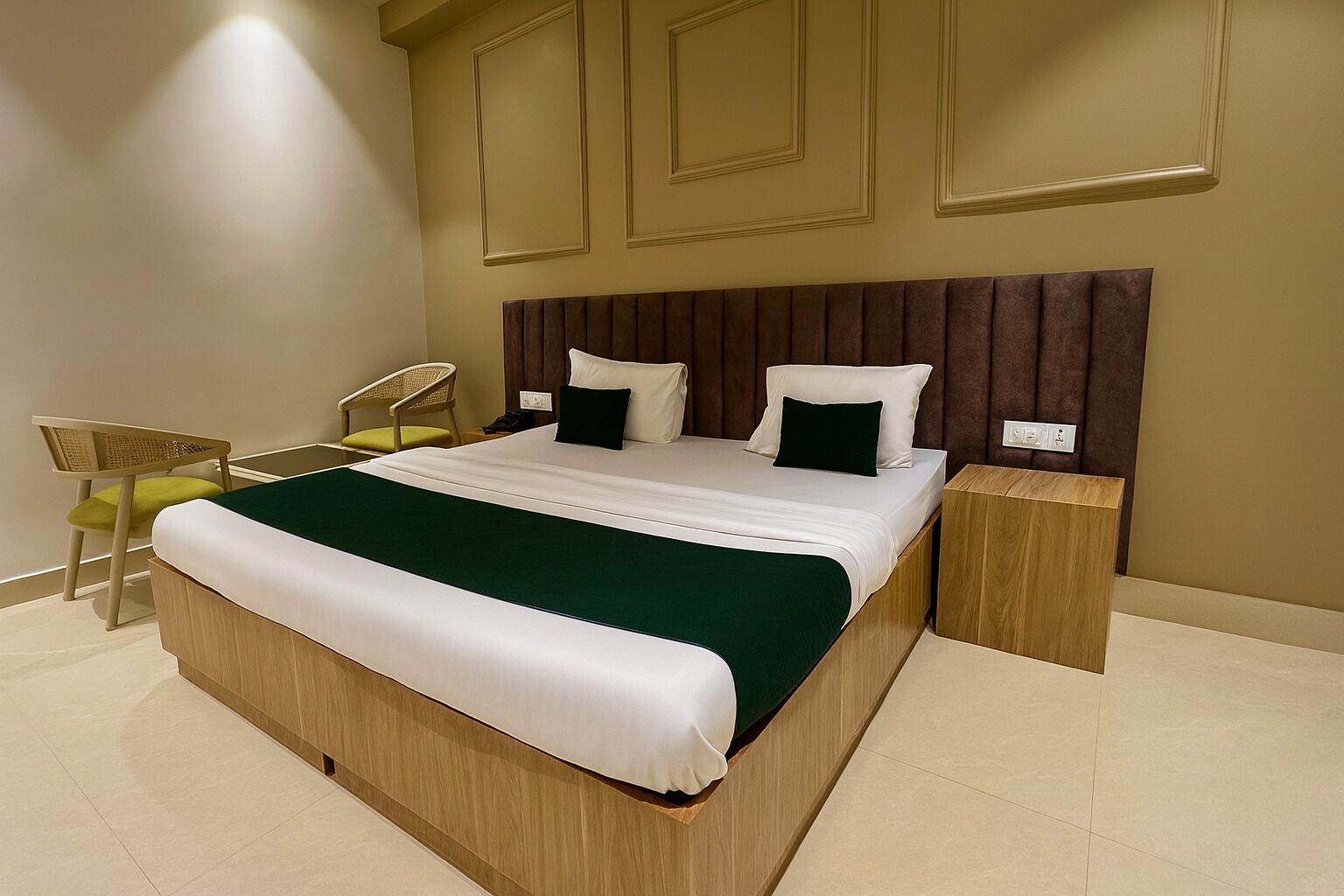 A modern hotel room with a large bed, wooden headboard, two bedside tables, a chair, and a small desk.