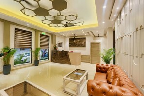 A modern lobby with a reception desk, seating area, and lockers. - Hotel Citi Continental (New Delhi)