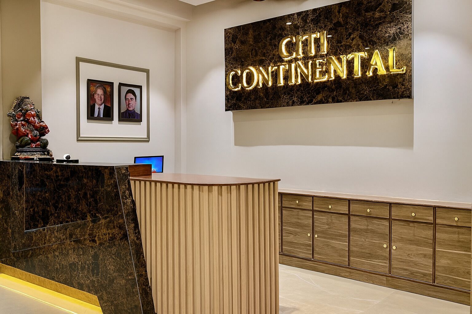Ein Empfangstisch mit Marmorplatte, einer Holzvertäfelung und einem an der Wand befestigten Schild mit der Aufschrift 'CITI CONTINENTAL'.