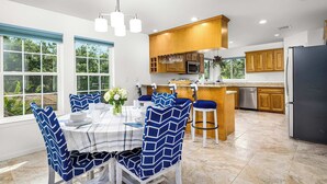Una cocina moderna con armarios de madera, una isla central y un comedor con sillas azules y una mesa preparada para cuatro.