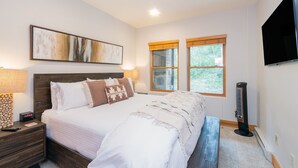 A bedroom with a bed, bedside tables, a wall-mounted TV, and a window with blinds. - Bear Creek Lodge 210 1 Bedroom Condo (Telluride)