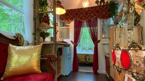 Una habitación acogedora con un sofá rojo, un refrigerador antiguo y un armario de madera.