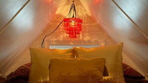Una carpa con una cama, almohadas y una lámpara colgante.
