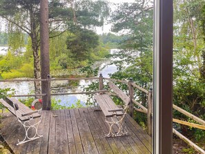 A wooden deck with metal railings overlooking a river, surrounded by trees and vegetation. - 4 Star Holiday Home in Tyringe (Västra Torup)