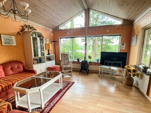 A living room with a sofa, a glass coffee table, a fireplace, and large windows.