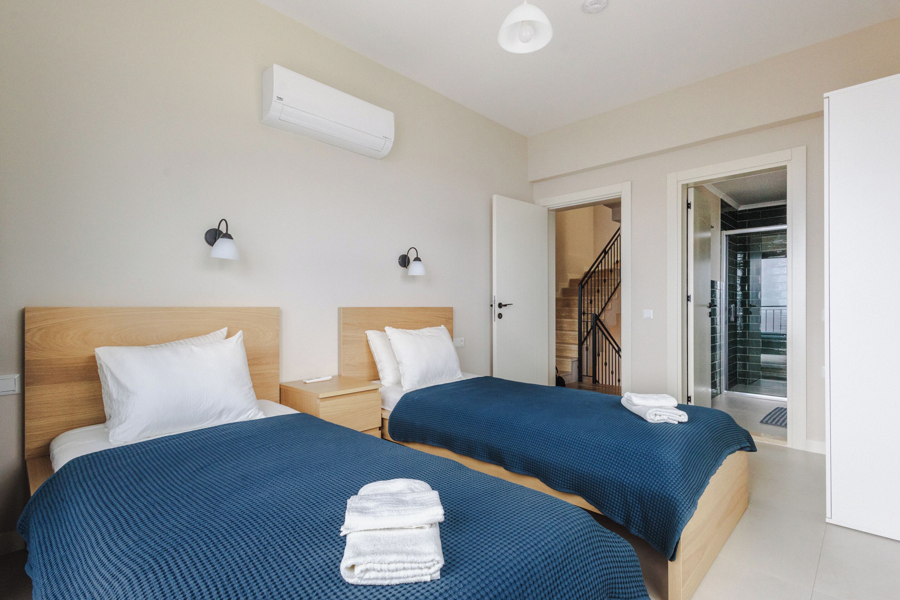 A hotel room with two beds, a staircase, and an air conditioning unit.