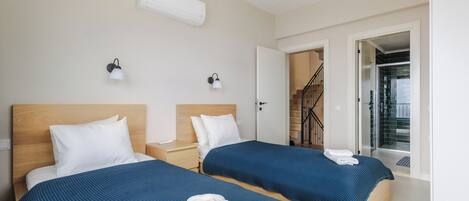 A hotel room with two beds, a staircase, and an air conditioning unit.