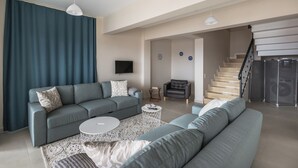 A modern living room with a grey sofa set, a coffee table, and a TV mounted on the wall.